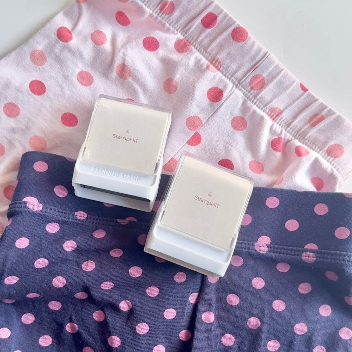 Two StampHIT Name Stamps laid out on two pairs of pajamas