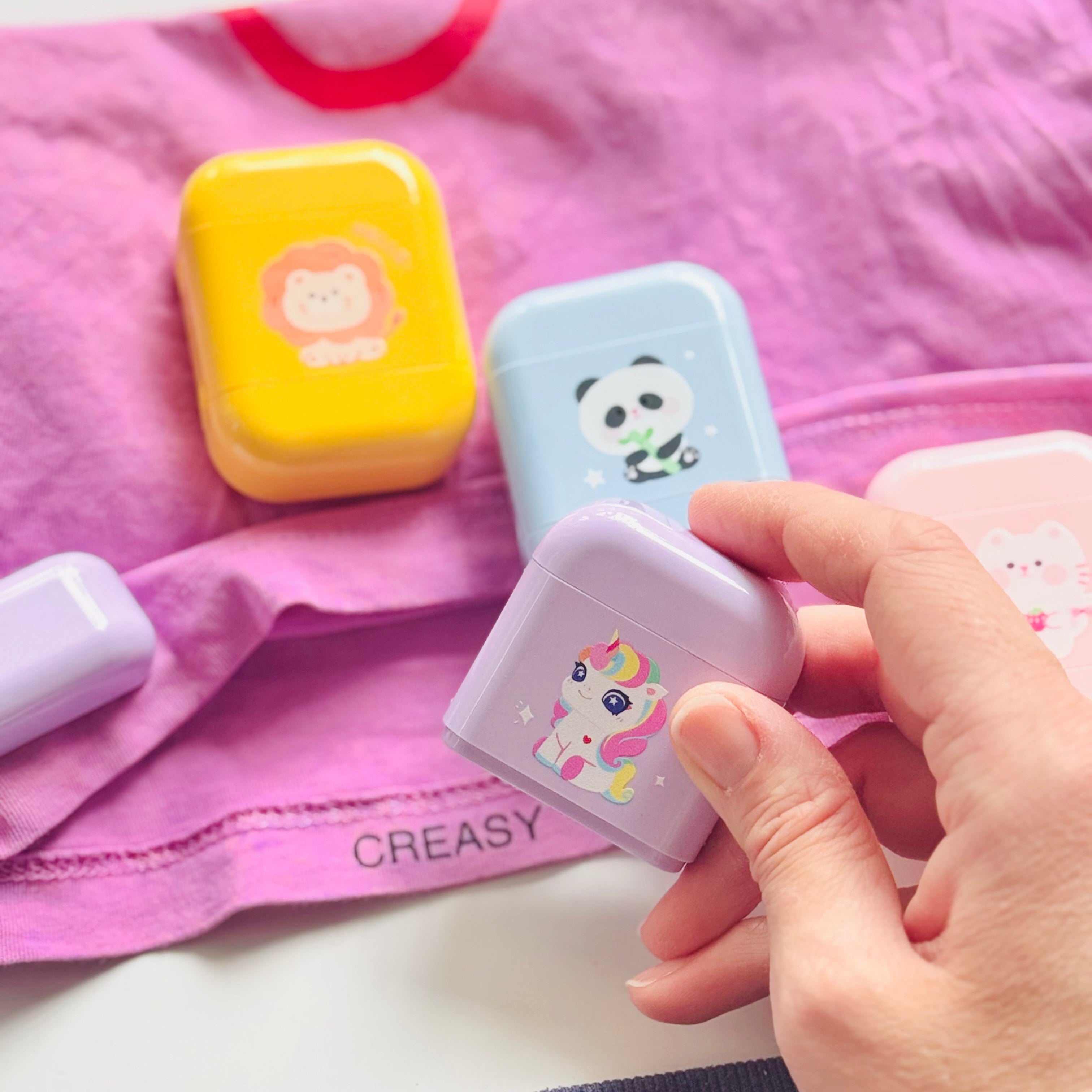Coloured name stamps on a pink shirt, on hand holding a purple stamp