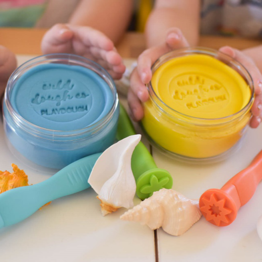 Young hands hold Blue and Yellow play dough in small containers