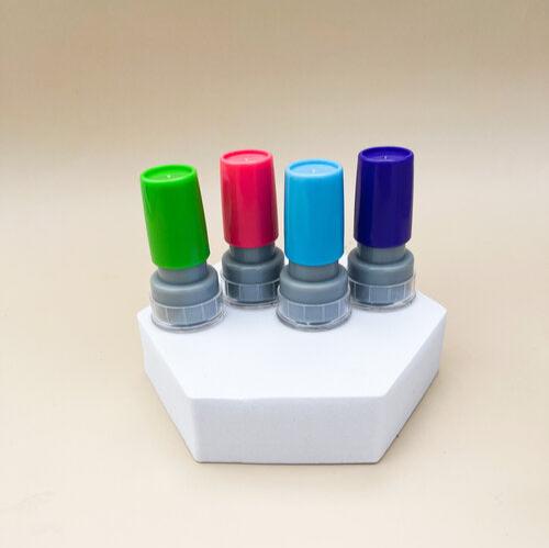 Green, red, light blue and blue card stamps sit side by side atop a pentagonal prism