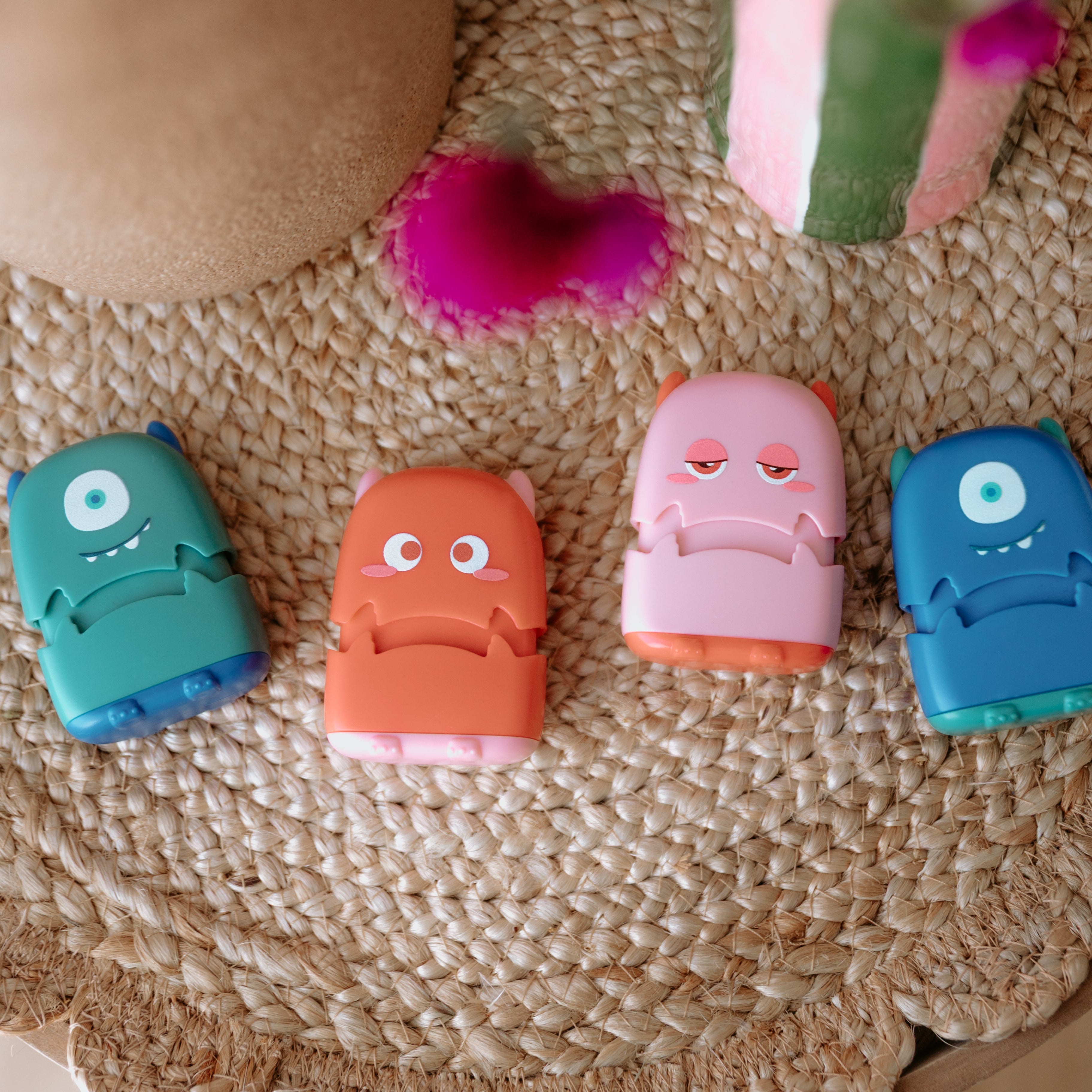 Four monster fabric name stamps lay facing up. A green one, red one, pink one and blue one