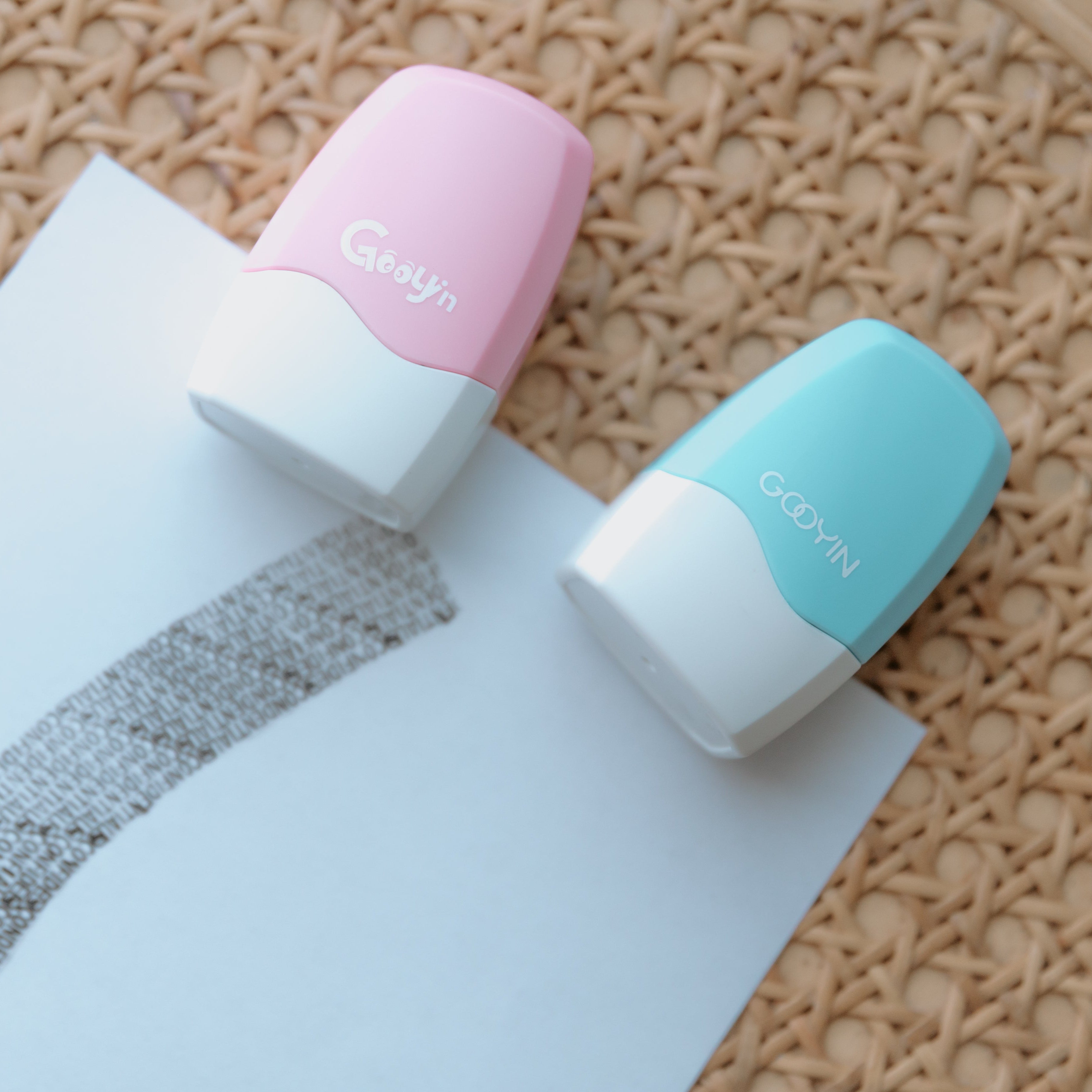 Two privacy stamps one pink, one light blue with 'Gooyin' printed on them laying on a sheet of paper with the stamps ink displaying 'confidential' pressed onto it