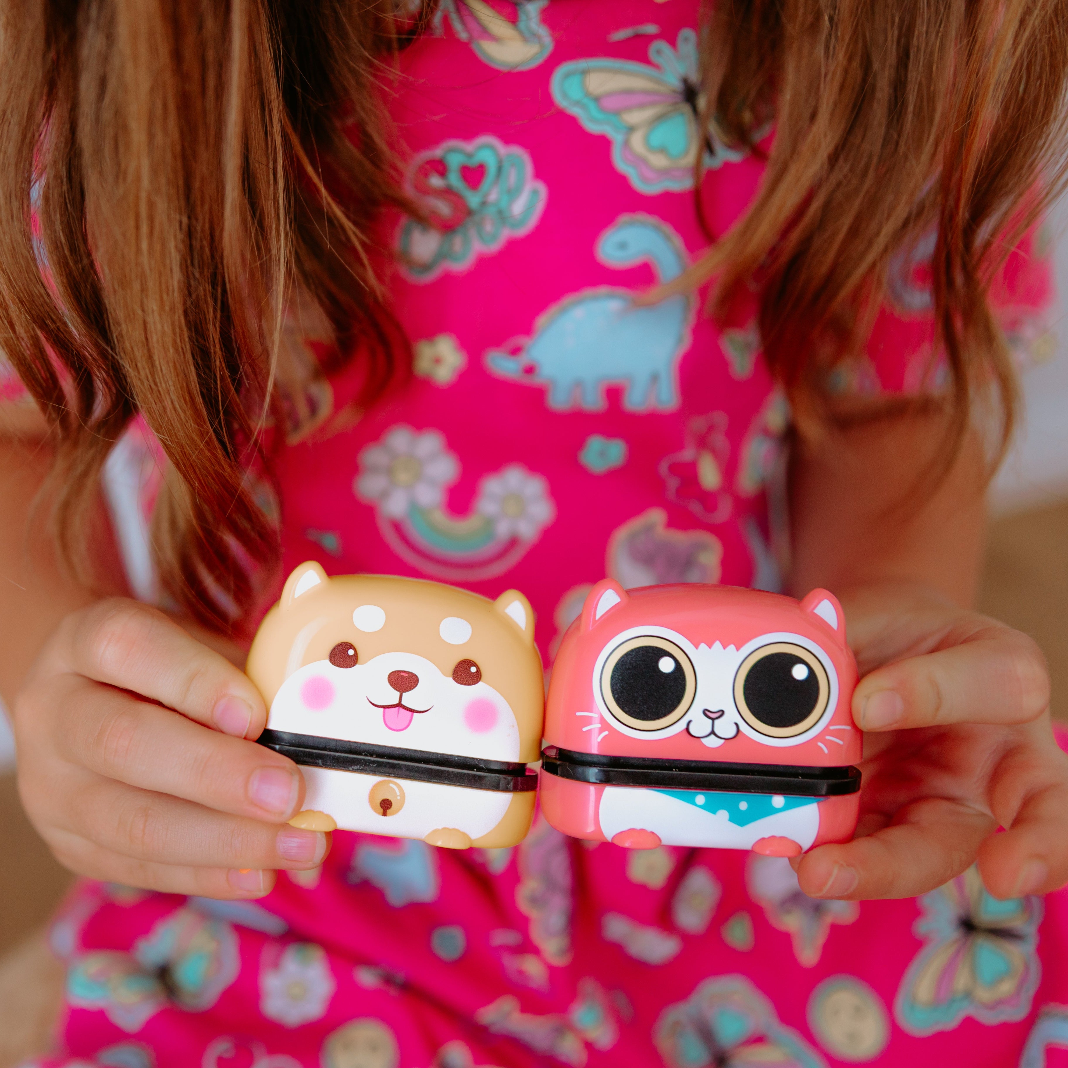 A person holding two animal name stamps displaying characters on them. One a dog and the other a cat