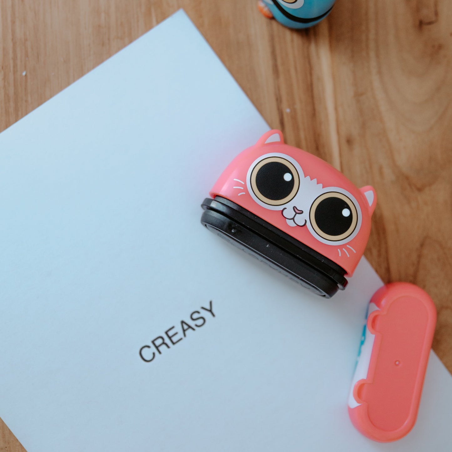 An animal name stamp displaying a cat laying open on a sheet of paper that has 'CREASY' printed on it