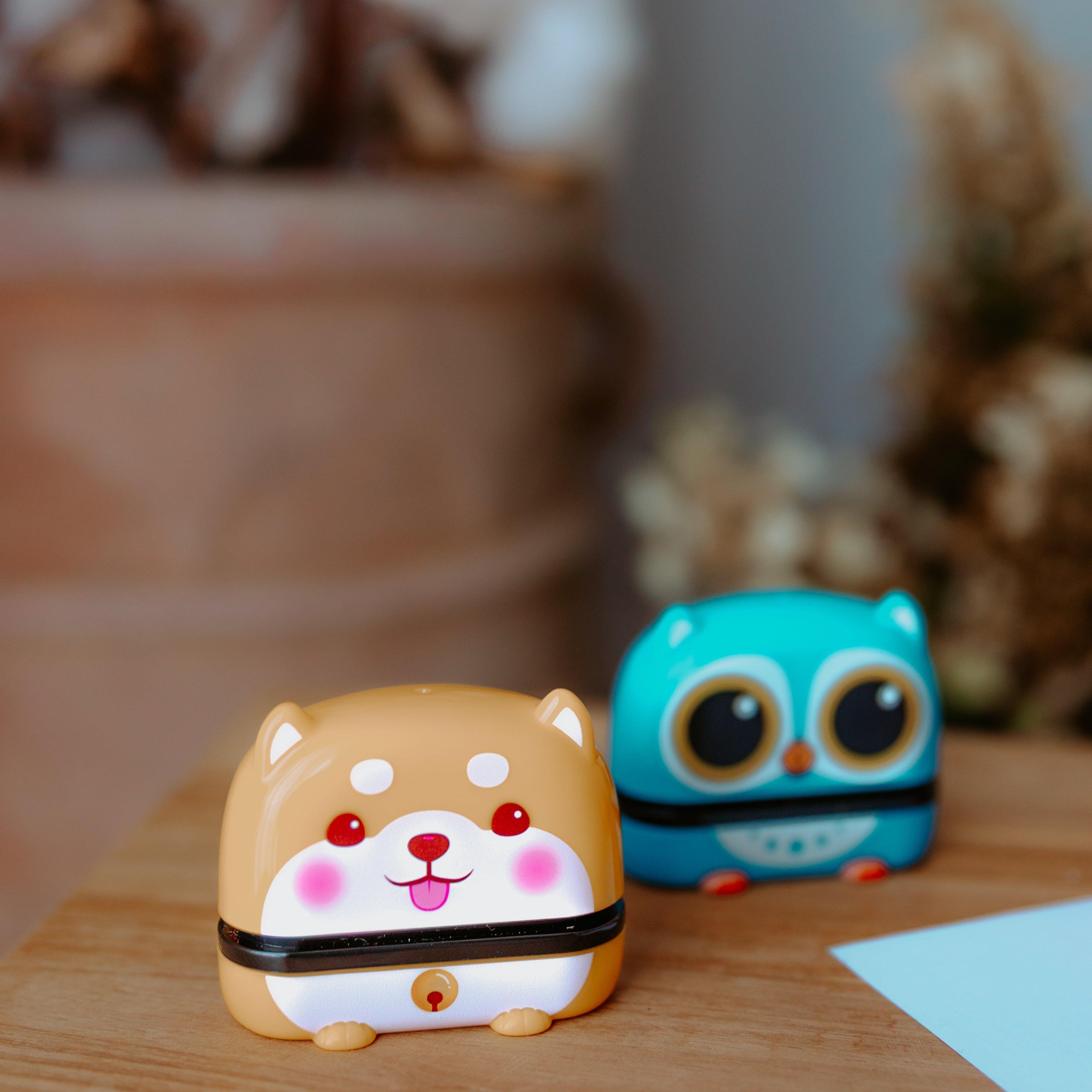 Two animal name stamps sitting on a table displaying characters. One is a dog and the other one is a bird which is sitting out of focus