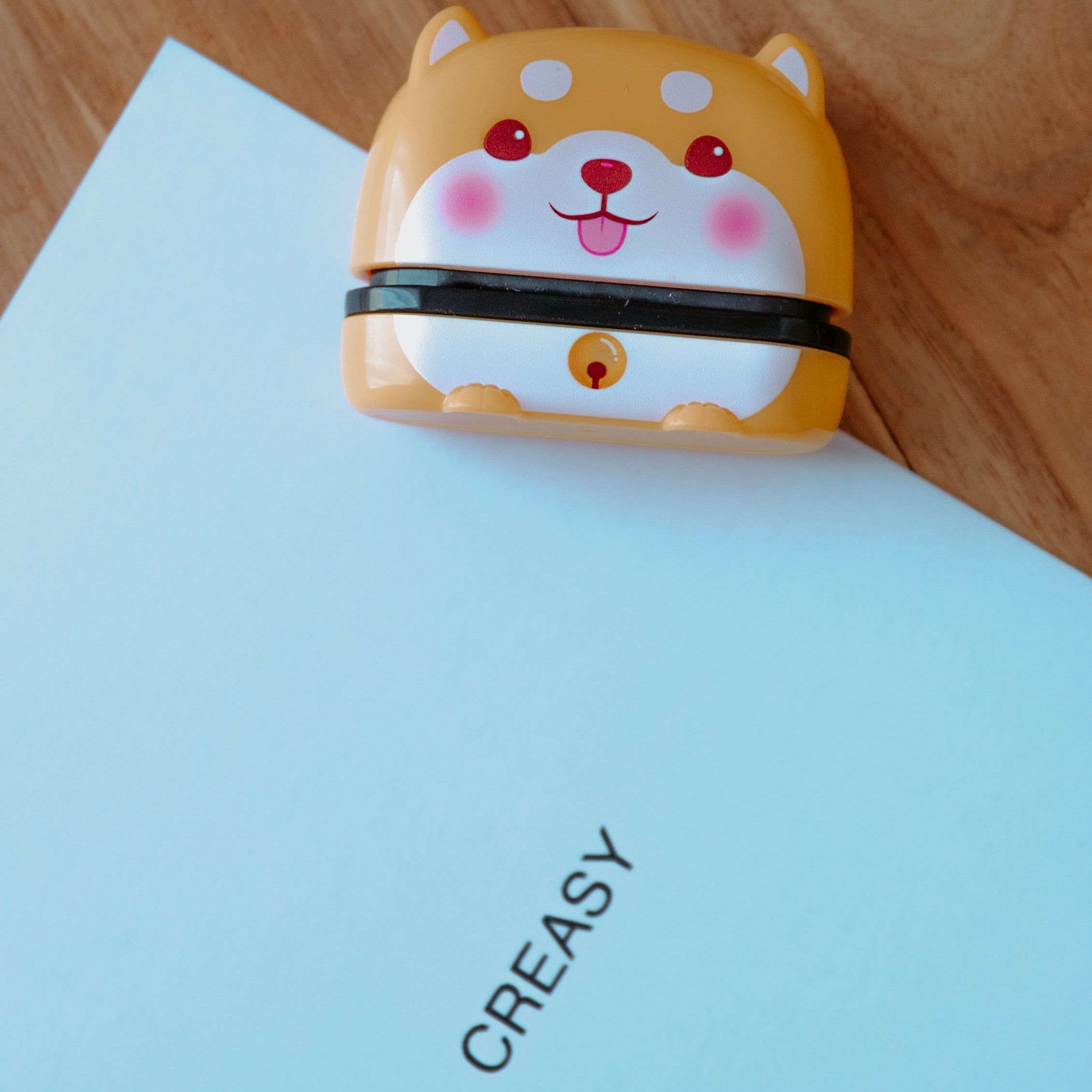 An animal name stamp displaying a dog laying on a sheet of paper with print that displays 'CREASY' on it