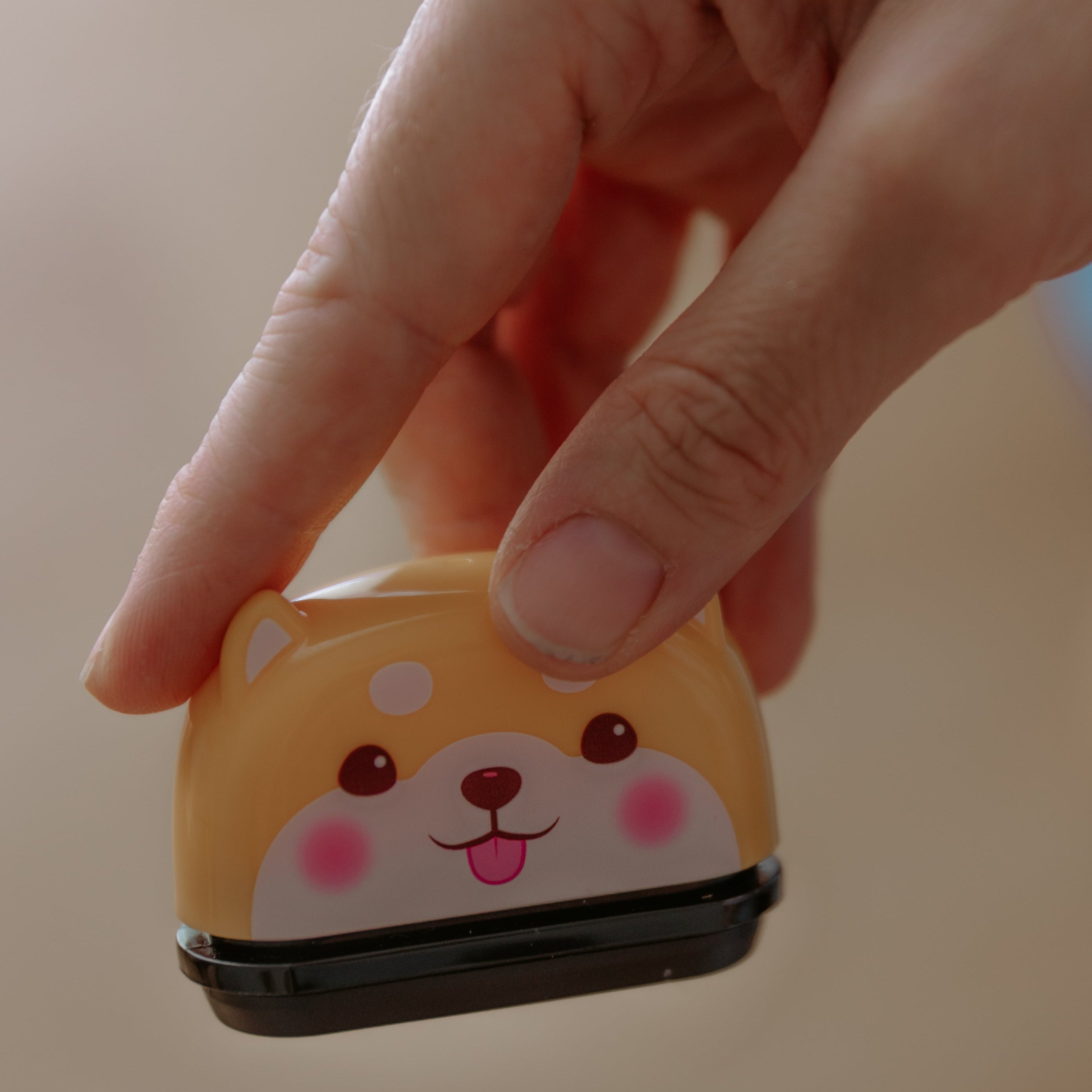 A person holding an open animal name stamp displaying a dog in the air