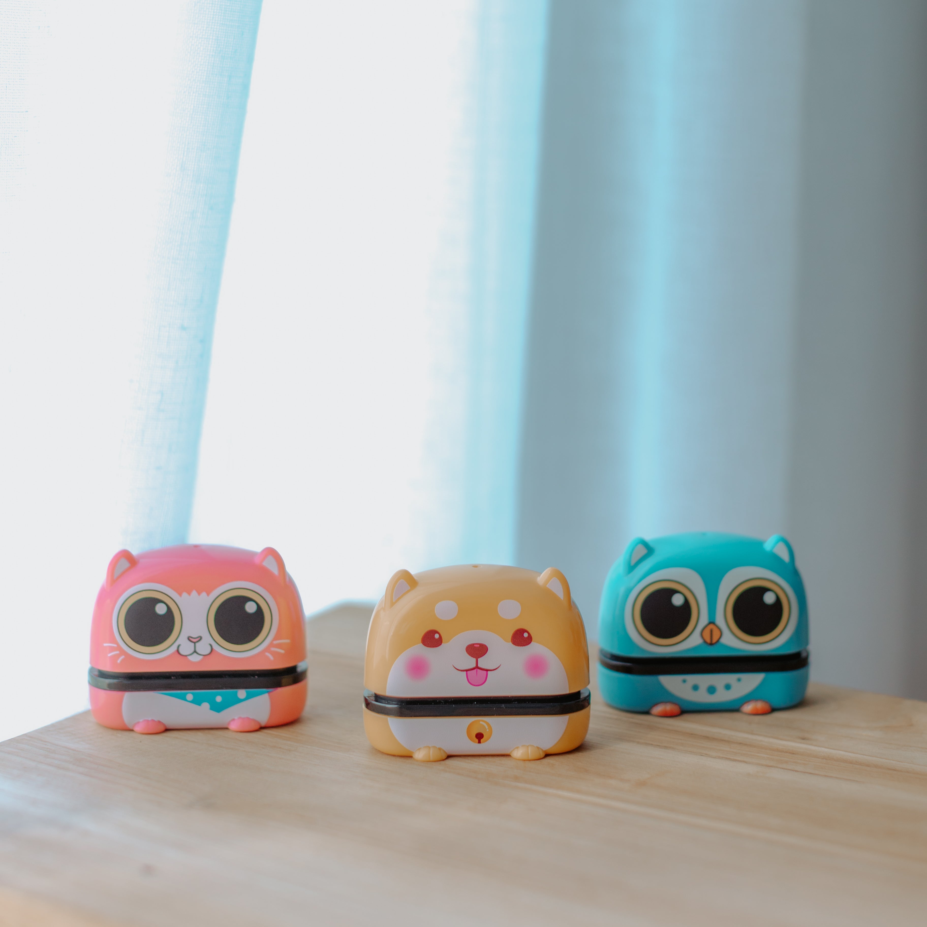 Three animal name stamps sitting on a table side by side each displaying characters, a cat, dog and bird