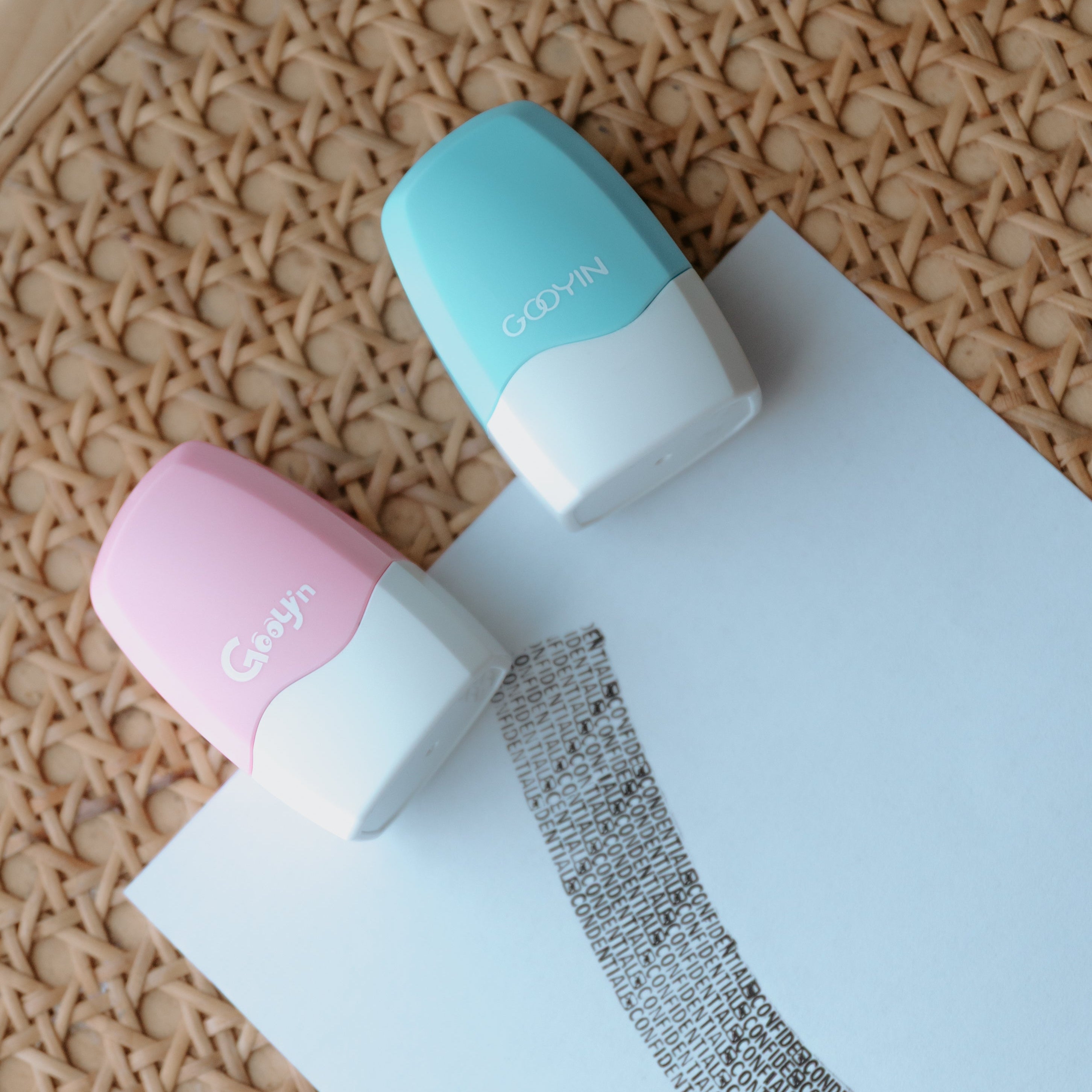 Two privacy stamps one pink, one light blue with 'Gooyin' printed on them laying on a sheet of paper with stamp ink displaying 'confidential' pressed on