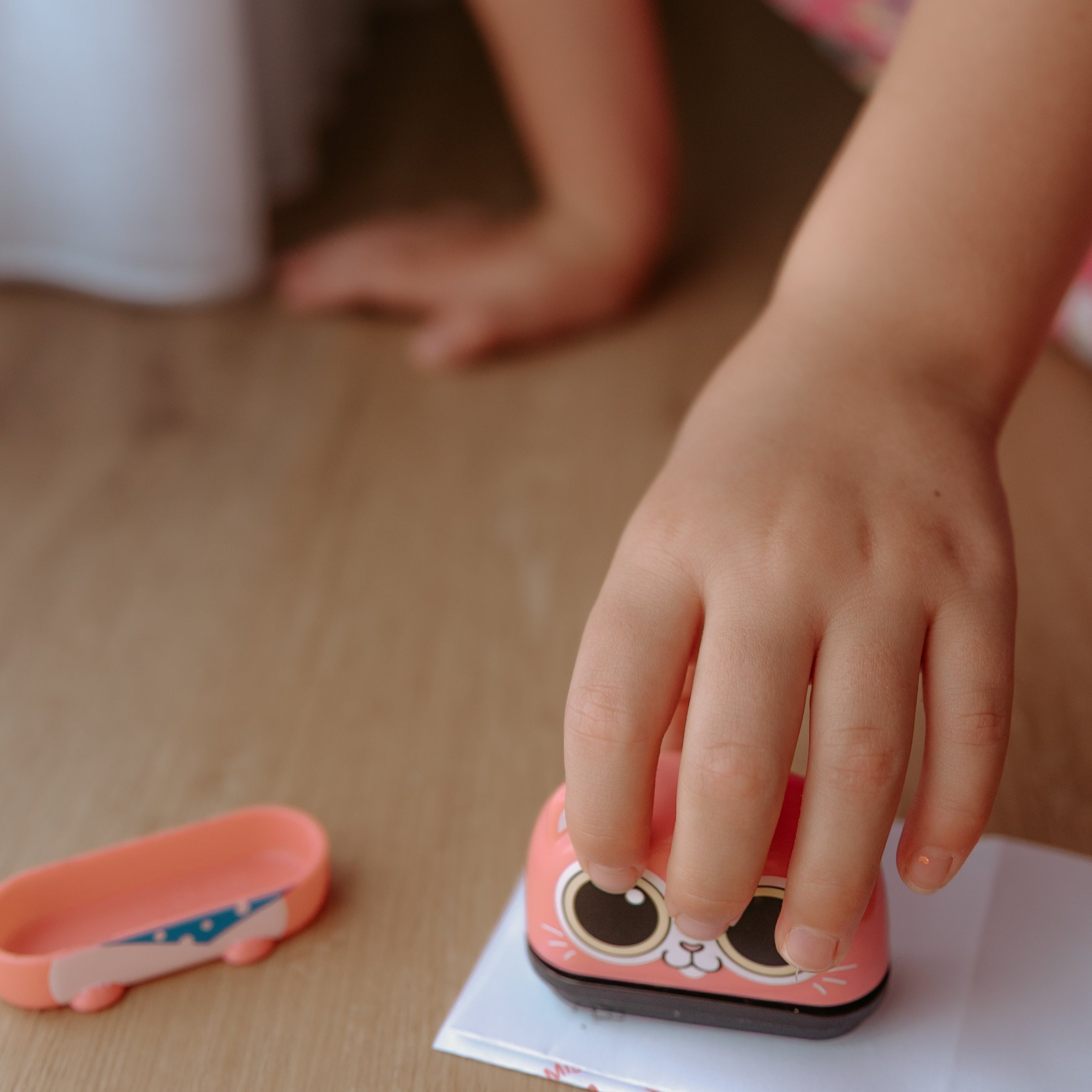 A person pressing an animal name stamp displaying a cat on a sheet of paper