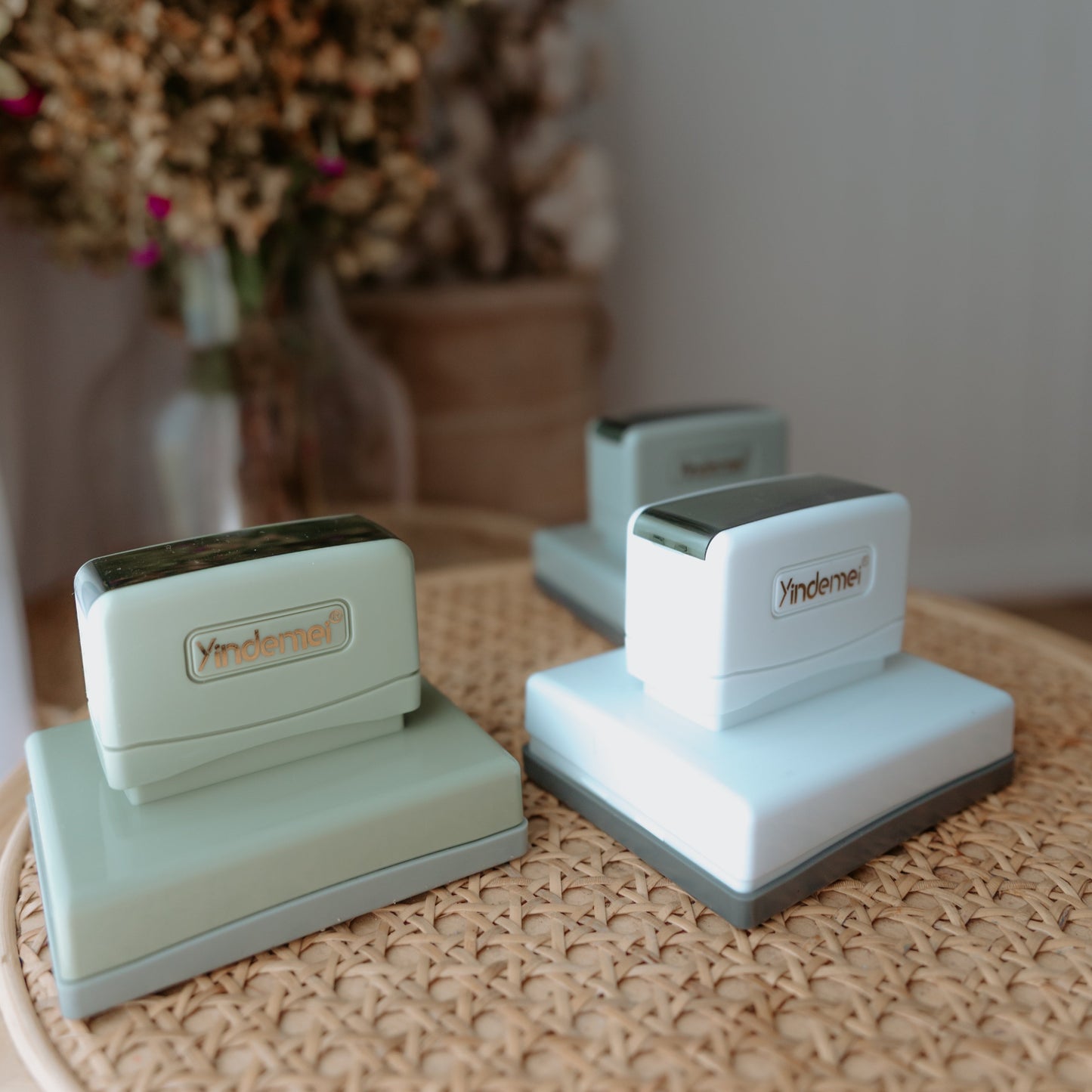 White, green and grey business stamps with squared bases sitting on a table with 'Yindemei' text displayed on them
