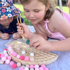 Two young children play with wooden play dough set