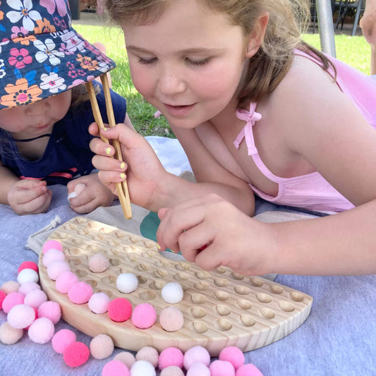 Two young children play with wooden play dough set